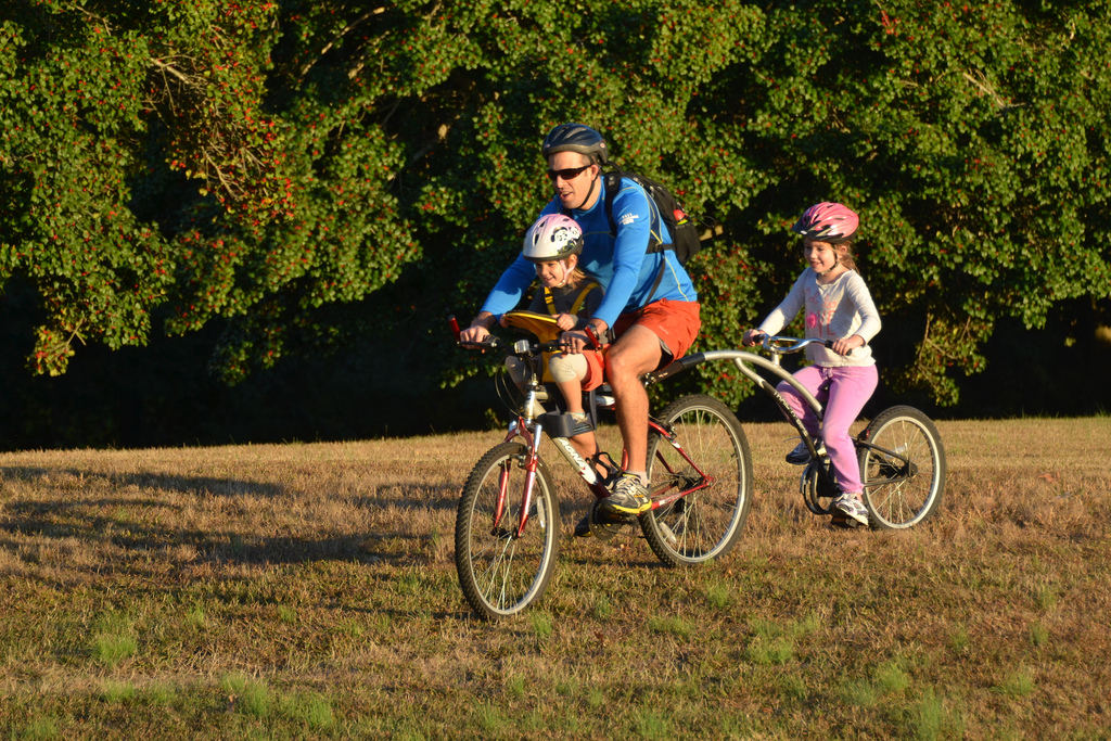 A father and his two kids riding a bicycle